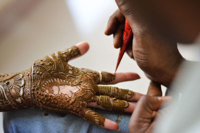 Cropped image of artist applying henna tattoo on woman hand