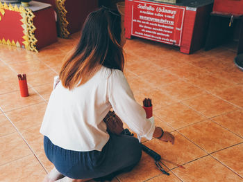 Rear view of woman sitting on tiled floor