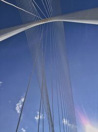 Low angle view of suspension bridge against blue sky