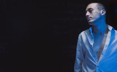 Portrait of man standing against black background