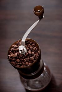 High angle view of coffee beans in grinder on wooden table