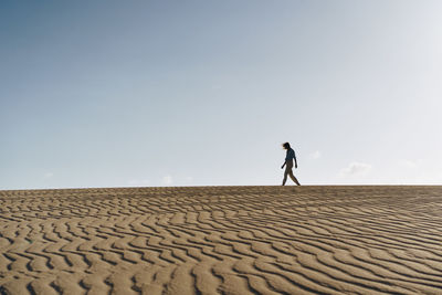 Full length of man walking on desert against sky