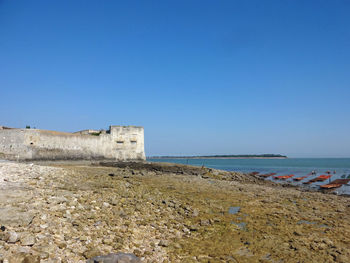 Scenic view of beach against clear blue sky