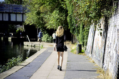 Woman walking on pathway along trees