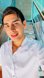 Portrait of smiling young man on staircase