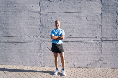 Full length portrait of young man standing against wall