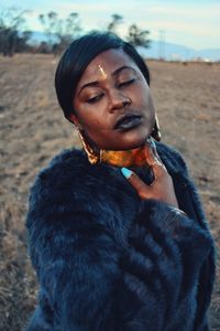 Young woman wearing jewelry and fur coat on field