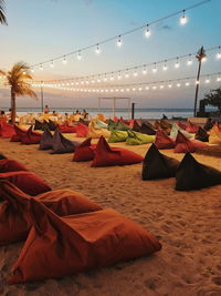 Chairs at beach against sky during sunset