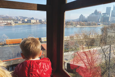 Rear view of boy looking through glass window