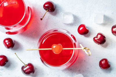Cocktail with cherry and ice, an aperitif with a garnish and fresh berries, overhead flat lay shot