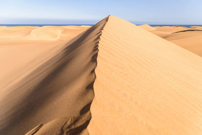 Sand dunes in desert against clear sky