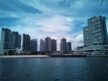 Sea by buildings against sky in city