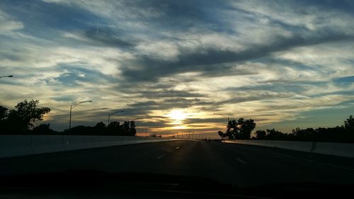 Cars on road against cloudy sky