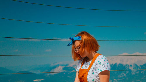 Woman standing against blue sky