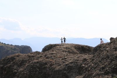 People standing on rock against sky