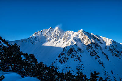 Scenic view of snowcapped mountains against clear blue sky