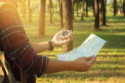 Close-up of hiker holding compass and map on field