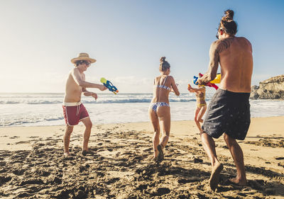 Full length of friends on beach against sky