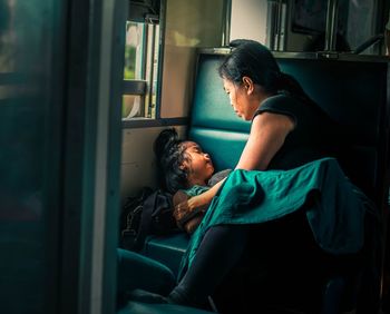 Mother sitting by sleeping daughter in train