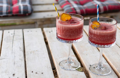 Close-up of two red cocktails in vintage glasses on white pallet table in bar