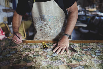 Midsection of artist making design on textile at workshop