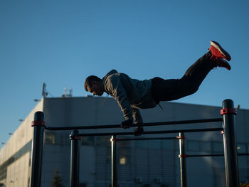 Low angle view of woman standing on railing against clear sky