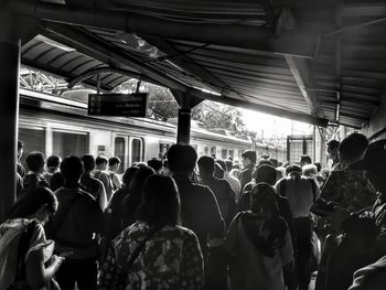 Rear view of people standing on road in city