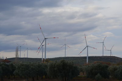 Wind turbines on field against sky