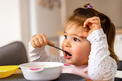 Cute girl eating food at table