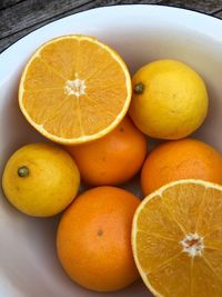 Close-up of halved and whole oranges in bowl