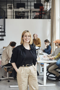 Portrait of confident businesswoman with hands in pocket standing at tech start-up office