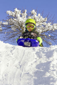 Excited boy sledding on snow covered landscape