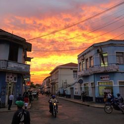 People on city street against orange sky