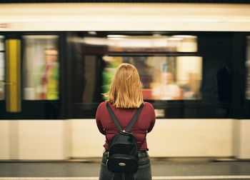 Rear view of woman standing against train