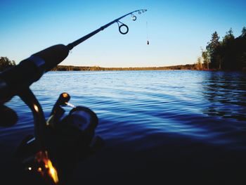 Man fishing in lake against clear sky