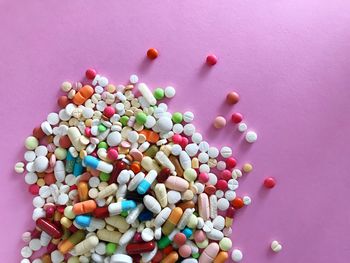 High angle view of colorful medicines on pink background