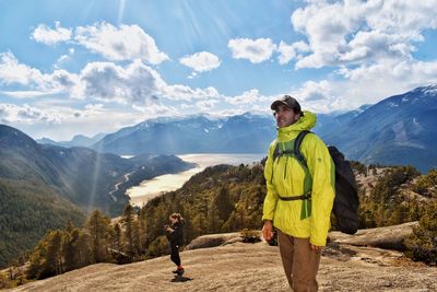 Hikers standing on field against sky during sunny day