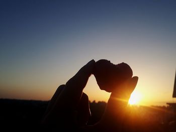 Silhouette hand against sky during sunset