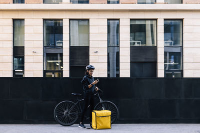 Delivery person using mobile phone by bicycle