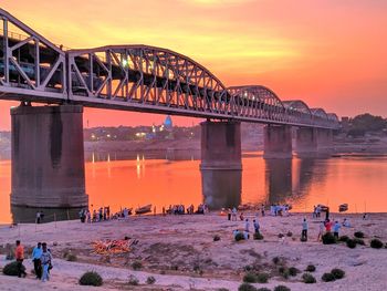 People on bridge against sky during sunset