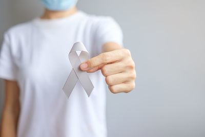 Midsection of woman holding paper against white background