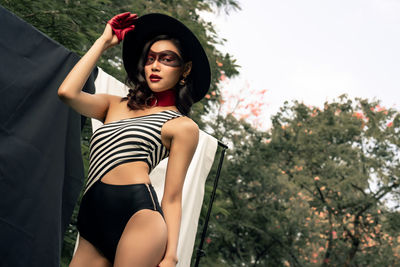 Portrait of beautiful young woman against trees