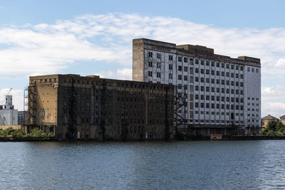 Building by river against sky in city