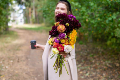Autumn bouquet of flowers and a cup of tea in the hands of a cute girl
