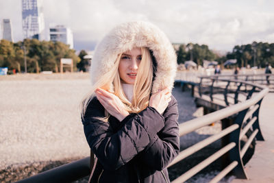 Happy smiling blonde girl is cold in coat with fluffy hood. portrait. high quality photo