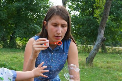 Mother holding bubble wand with son at park