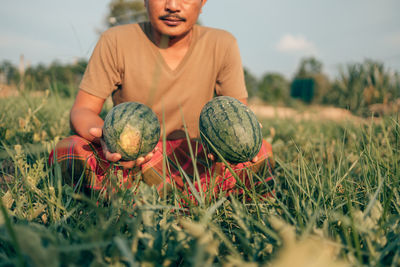 Full length of man holding corn on field