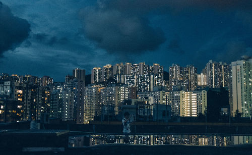 Illuminated modern buildings in city against sky at night