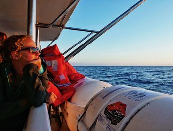 Woman with hand on chin looking at sea from boat sailing in sea