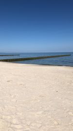 Scenic view of beach against clear blue sky